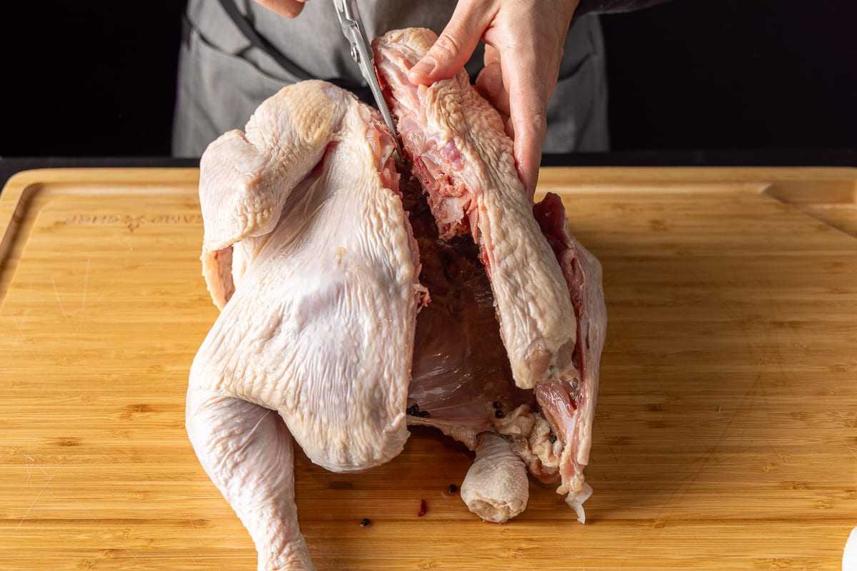 Spatchcock the turkey by removing the backbone using a sharp knife or kitchen shears
