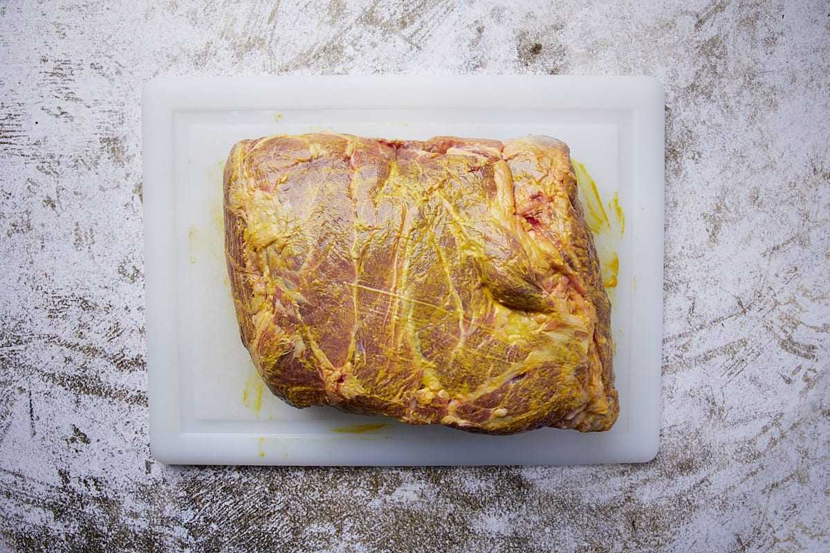 Rub a thin, even coating of yellow mustard on all sides of the pork